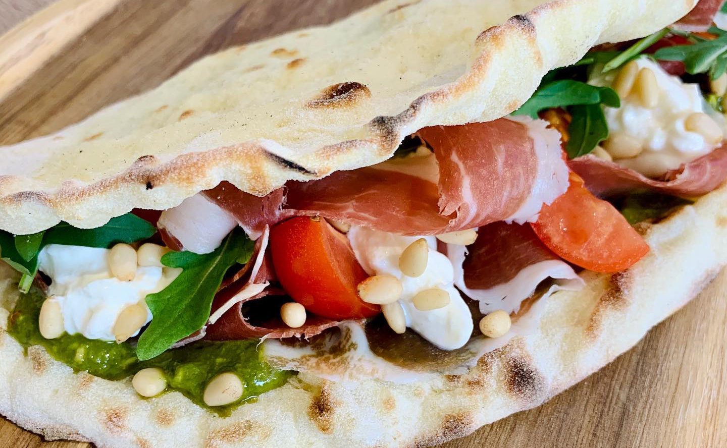 Une piadina fourrée de jambon cru, de tomate, de roquette et de crème